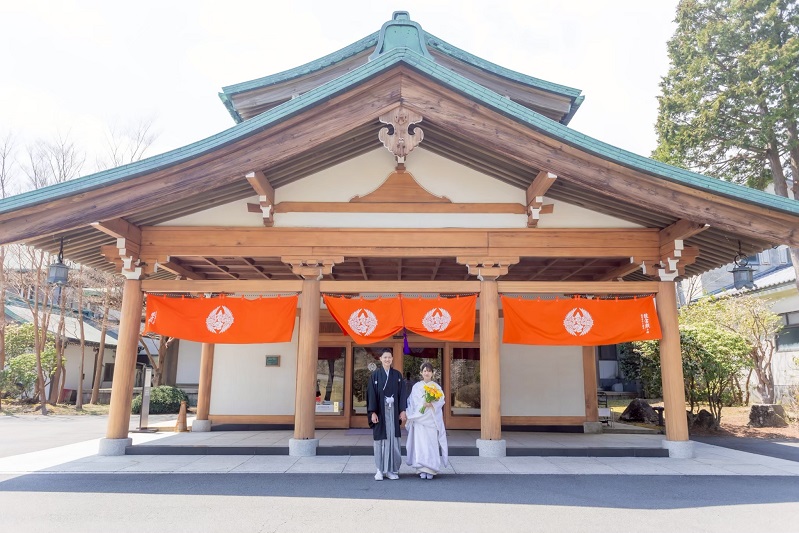 純日本風の旅館の前で和装姿の新郎新婦